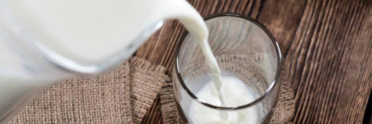 Pouring glass of milk from jug